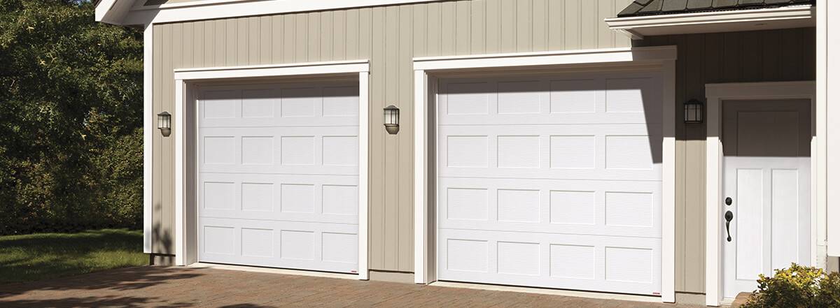 Beige traditional house with white classic garage doors Shaker-Flat on a sunny day